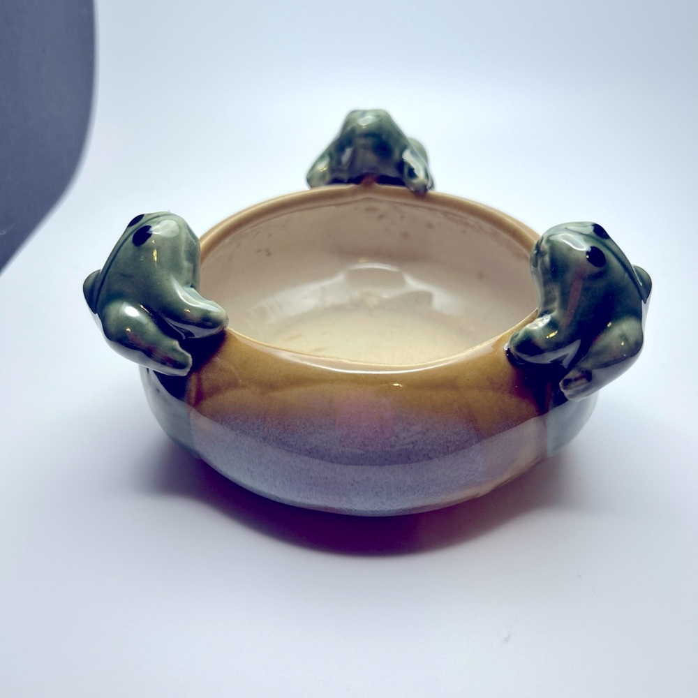 Three little frogs climbing inside a drip glaze planter.